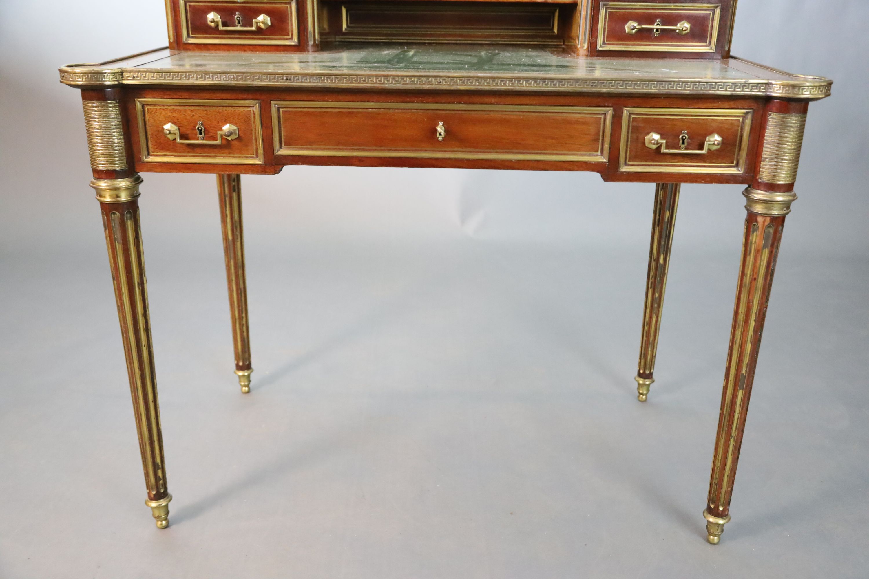 A French Louis XVI style brass mounted marble inset mahogany writing table, W.101.5cm D.7.5cm H.93.5cm